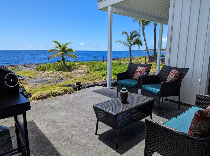 Lanai patio with wicker furniture and direct Pacific Ocean view, palm trees and lava shore