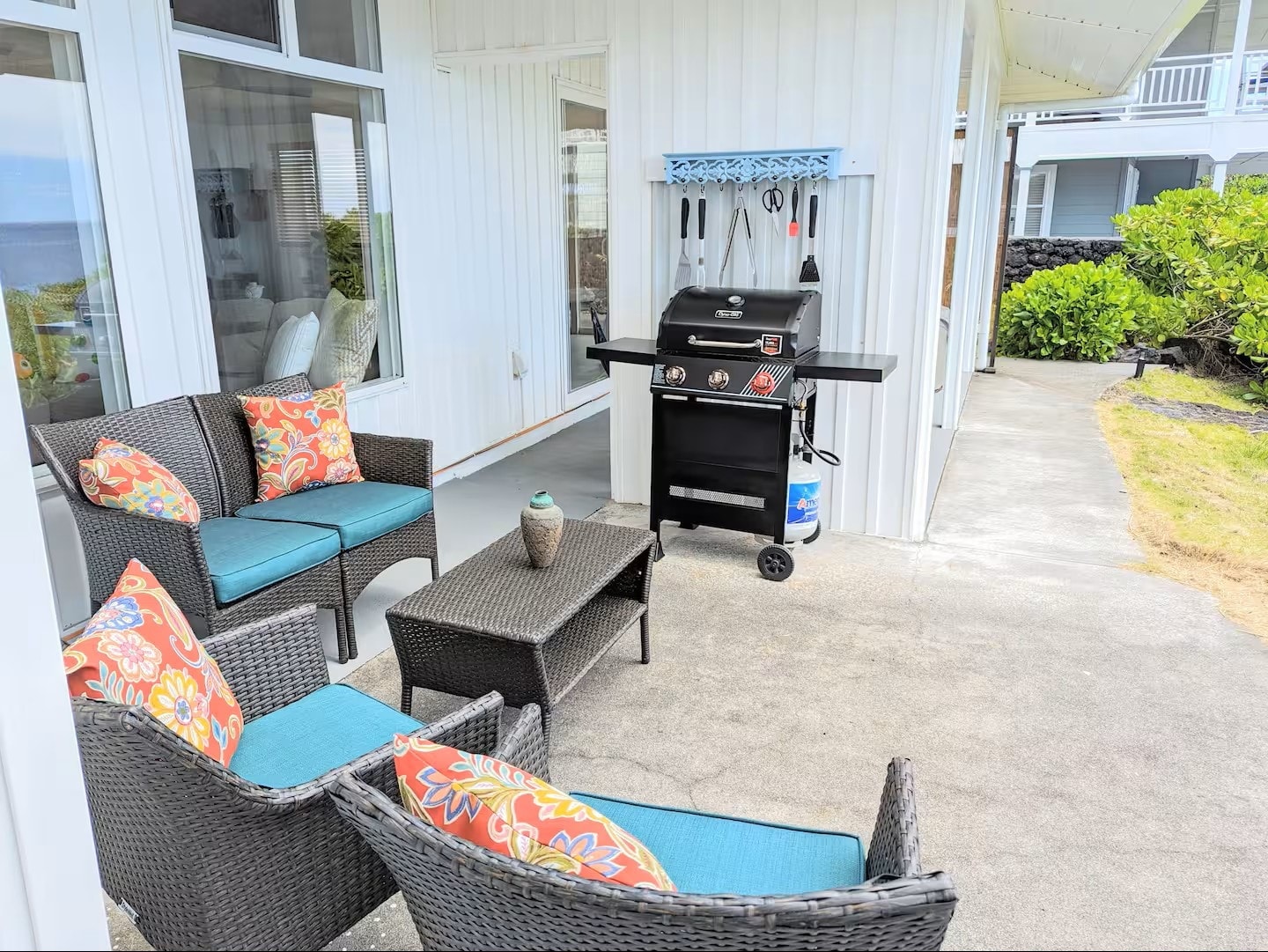 Wicker patio seating with colorful tropical cushions and gas BBQ grill on covered lanai